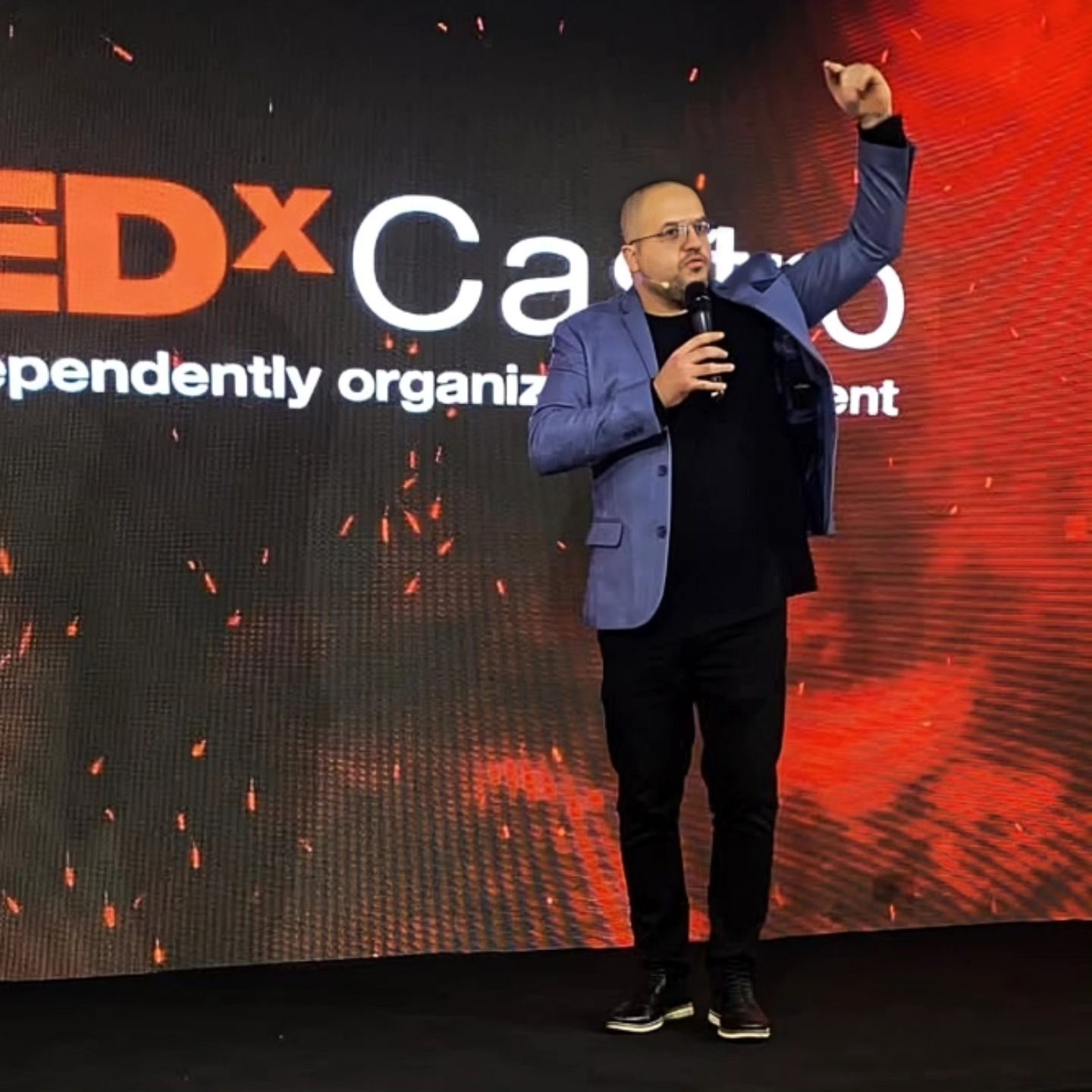 Douglas Tubarão palestrando no TEDx, com o microfone e o braço levantado